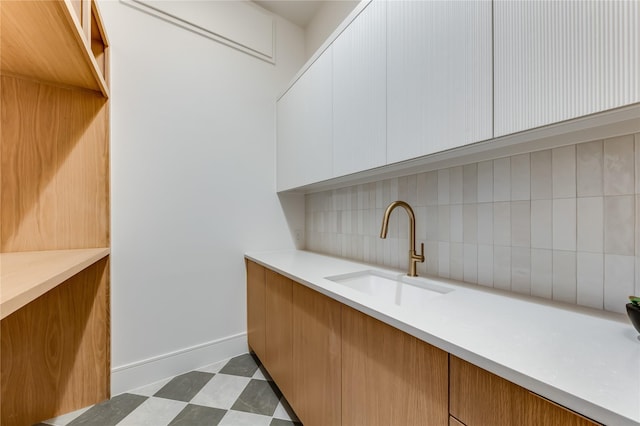 bar featuring tasteful backsplash, sink, and white cabinets