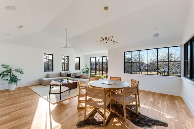 dining space with an inviting chandelier, vaulted ceiling, and light wood-type flooring