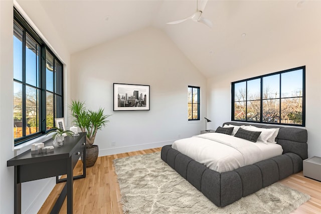 bedroom with multiple windows, high vaulted ceiling, ceiling fan, and light hardwood / wood-style flooring