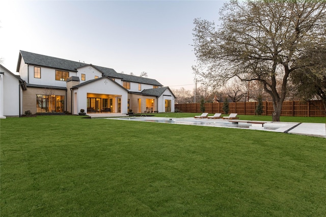 back house at dusk featuring a yard