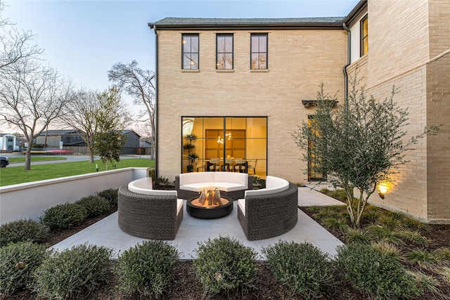 rear view of house with a patio and an outdoor living space with a fire pit