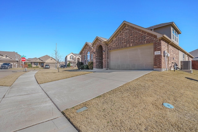 view of front of property featuring a garage, a front lawn, and central air condition unit