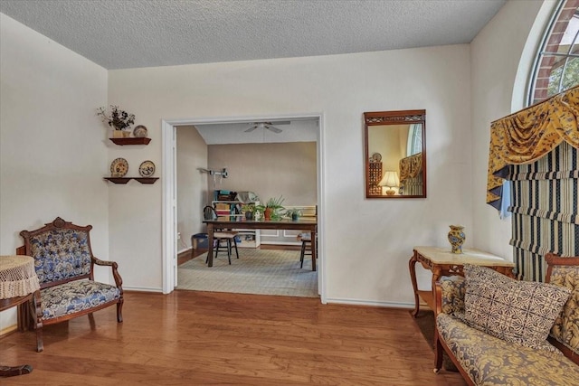 sitting room with ceiling fan, wood-type flooring, and a textured ceiling