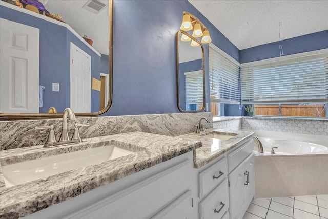 bathroom with tile patterned flooring, vanity, a bath, and a textured ceiling