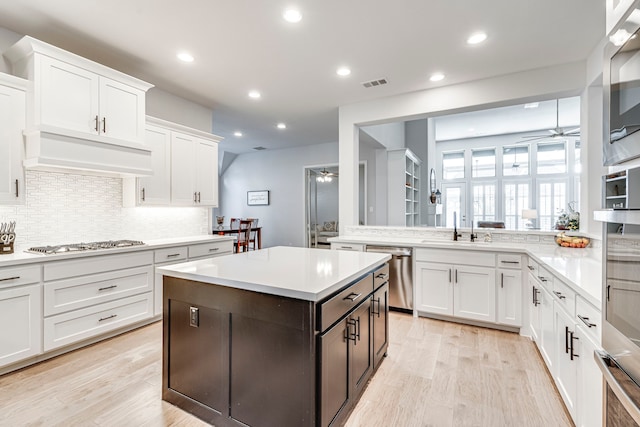 kitchen featuring custom exhaust hood, appliances with stainless steel finishes, white cabinets, and ceiling fan