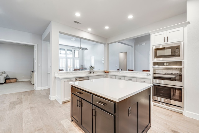 kitchen with stainless steel appliances, white cabinetry, light hardwood / wood-style floors, and kitchen peninsula