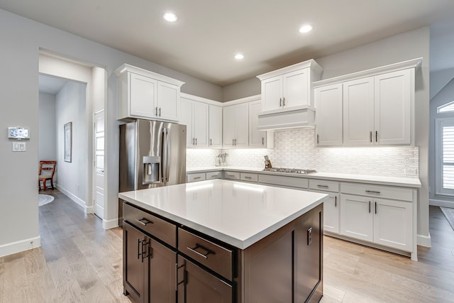 kitchen featuring white cabinetry, appliances with stainless steel finishes, custom range hood, and light hardwood / wood-style floors