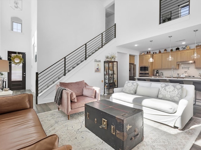 living room with a towering ceiling, sink, and light hardwood / wood-style floors