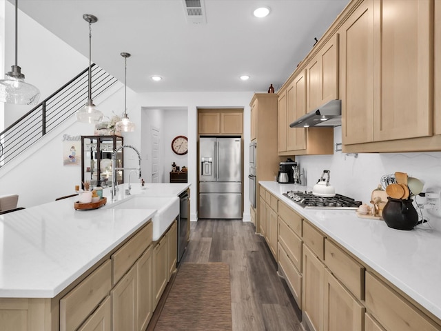 kitchen featuring visible vents, light brown cabinets, under cabinet range hood, a sink, and appliances with stainless steel finishes