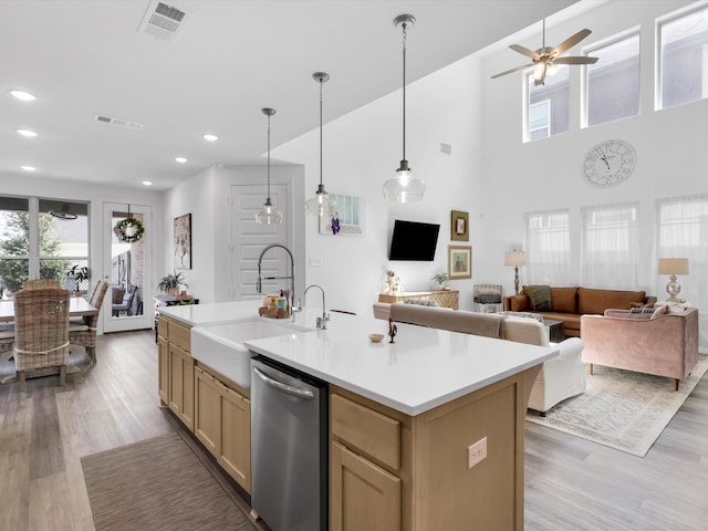 kitchen with visible vents, a sink, open floor plan, light countertops, and dishwasher