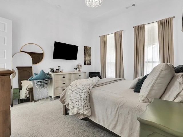 bedroom featuring an inviting chandelier, light colored carpet, and visible vents