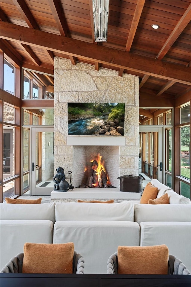 living room with beamed ceiling, wood ceiling, and a stone fireplace