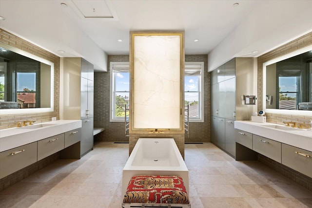 bathroom with a washtub, vanity, and brick wall