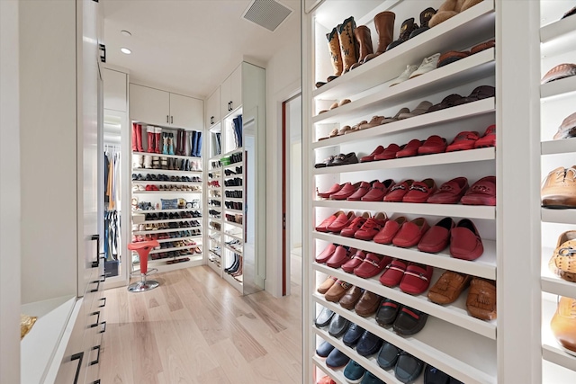 walk in closet with light hardwood / wood-style flooring