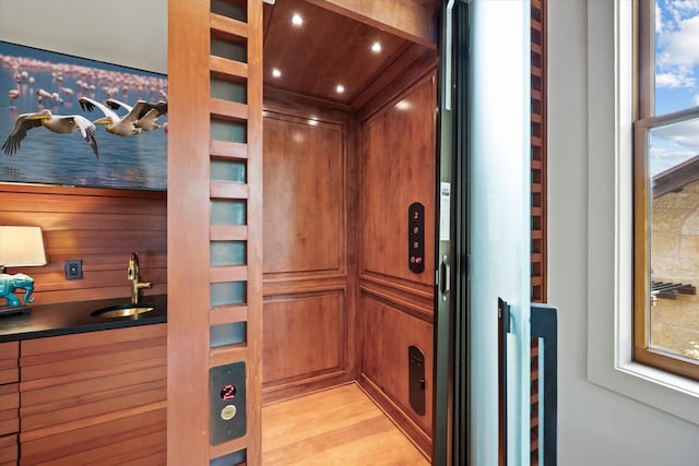 details featuring wood-type flooring, wooden walls, and sink