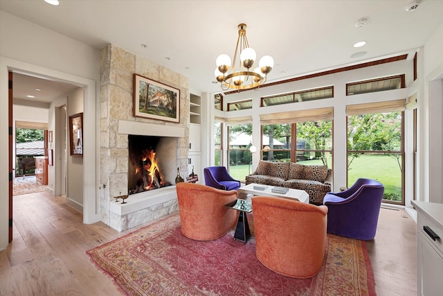 living room with a stone fireplace, a wealth of natural light, built in features, and light wood-type flooring