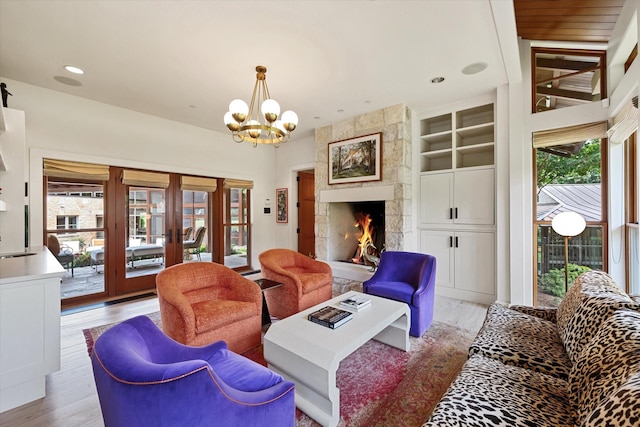 living room featuring a fireplace, sink, built in shelves, light wood-type flooring, and french doors