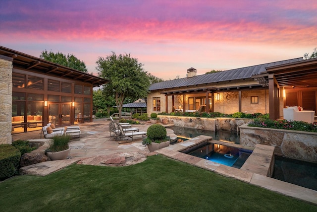 pool at dusk featuring a patio area and a lawn