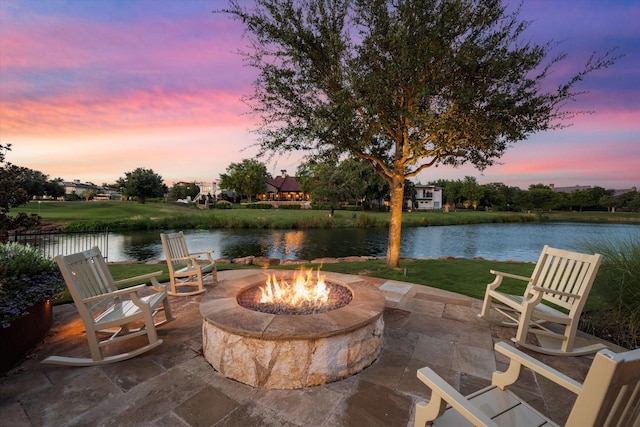 patio terrace at dusk featuring a water view and an outdoor fire pit