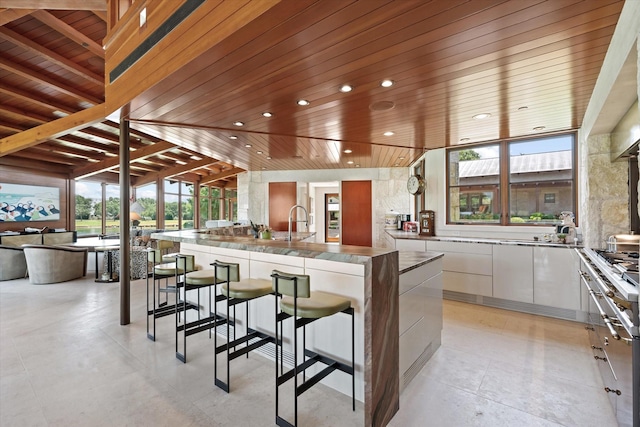 kitchen with white cabinetry, wooden ceiling, a breakfast bar, and a spacious island