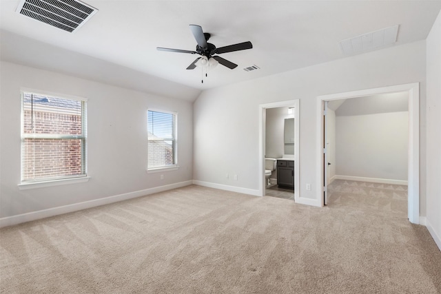 unfurnished bedroom with light carpet, vaulted ceiling, ceiling fan, and ensuite bathroom