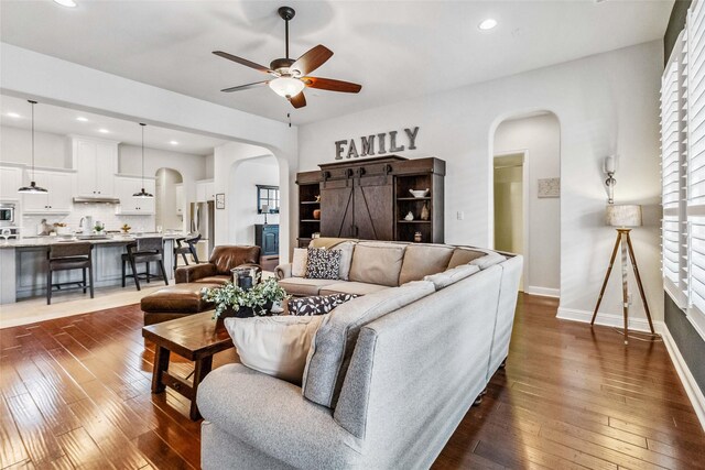 living room with dark wood-type flooring and ceiling fan