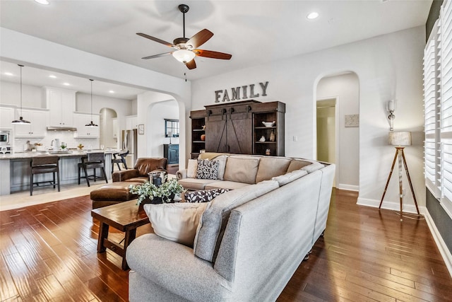 living room with ceiling fan and dark hardwood / wood-style flooring