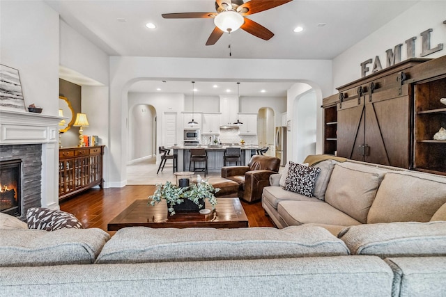 living room with a tiled fireplace, ceiling fan, and hardwood / wood-style flooring