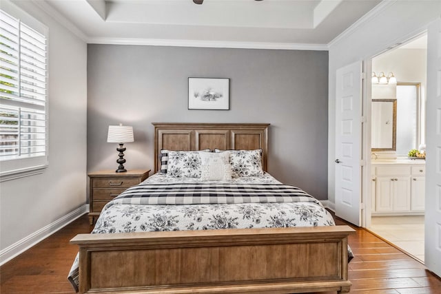 bedroom featuring crown molding, connected bathroom, a tray ceiling, and wood-type flooring