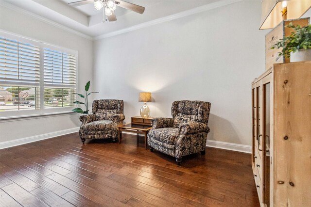 living area with dark hardwood / wood-style flooring, ornamental molding, a raised ceiling, and ceiling fan