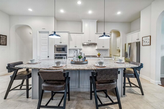 kitchen with stainless steel appliances, hanging light fixtures, and a large island with sink