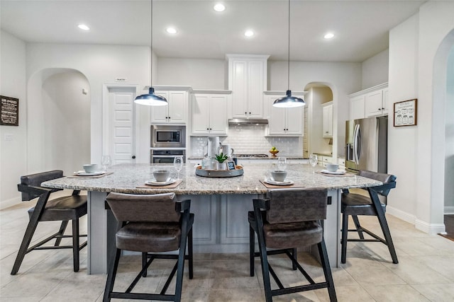 kitchen with stainless steel appliances, a spacious island, and decorative light fixtures