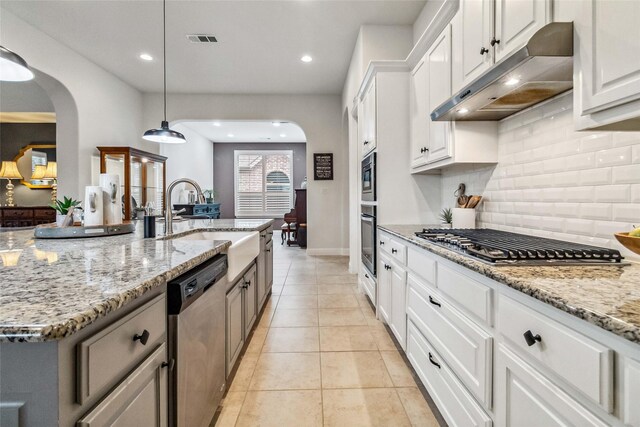 kitchen with pendant lighting, stainless steel appliances, a kitchen island with sink, and white cabinets