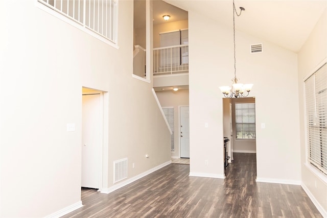 unfurnished living room with dark hardwood / wood-style flooring, a chandelier, and high vaulted ceiling