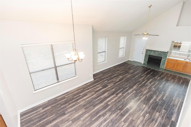 unfurnished living room with a tiled fireplace, ceiling fan with notable chandelier, vaulted ceiling, and dark hardwood / wood-style floors