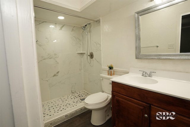 bathroom featuring hardwood / wood-style flooring, vanity, toilet, and a tile shower