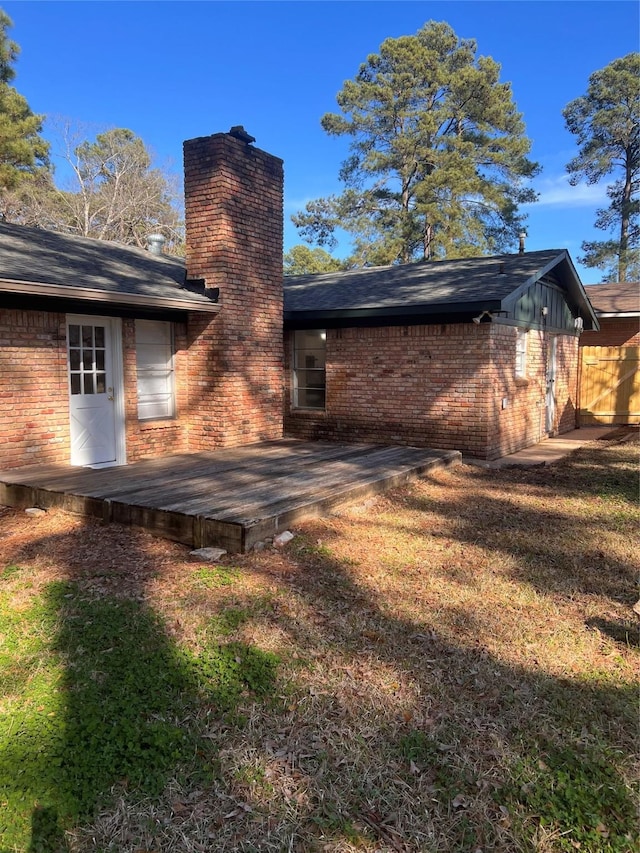 back of property with a wooden deck and a lawn