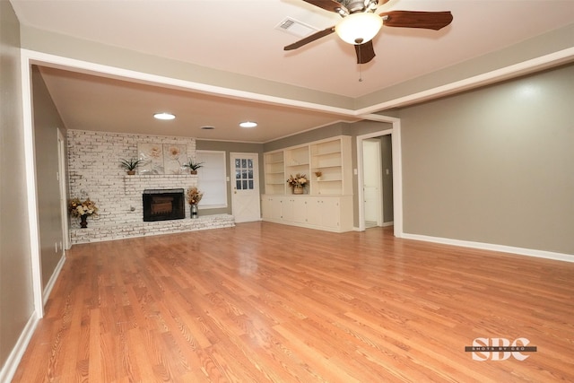 unfurnished living room featuring hardwood / wood-style flooring, ceiling fan, and a brick fireplace