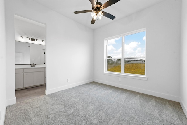 unfurnished bedroom featuring ensuite bathroom, sink, and light carpet