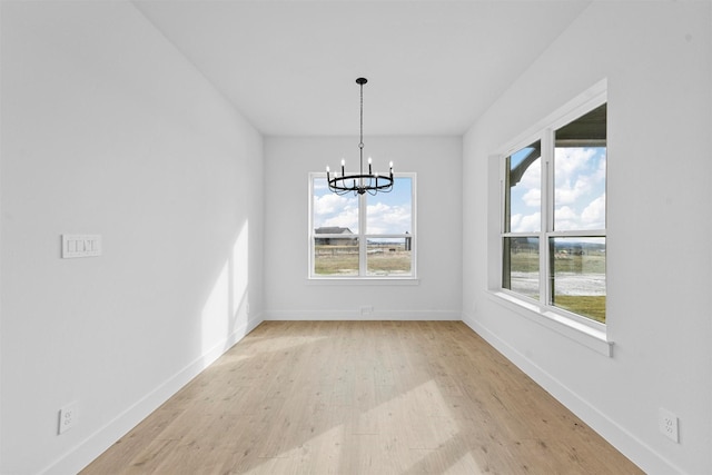 unfurnished dining area featuring an inviting chandelier and light hardwood / wood-style flooring