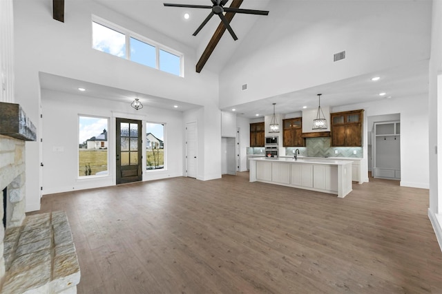 unfurnished living room with dark hardwood / wood-style flooring, sink, ceiling fan, and a fireplace