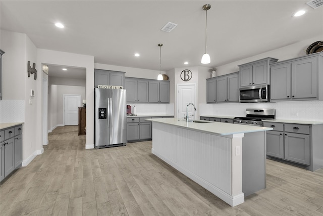 kitchen featuring pendant lighting, sink, a kitchen island with sink, and appliances with stainless steel finishes