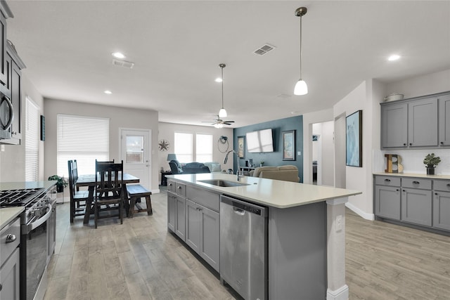 kitchen with an island with sink, sink, gray cabinetry, light hardwood / wood-style floors, and stainless steel appliances