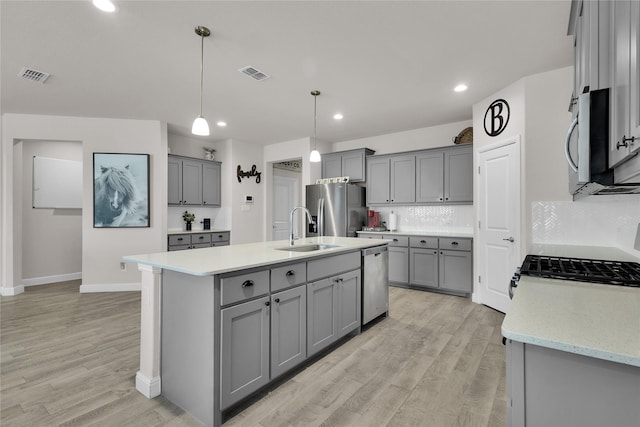 kitchen featuring sink, hanging light fixtures, gray cabinets, stainless steel appliances, and decorative backsplash