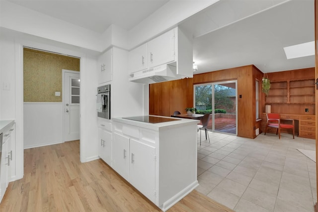 kitchen with white cabinetry, a skylight, black electric cooktop, and oven