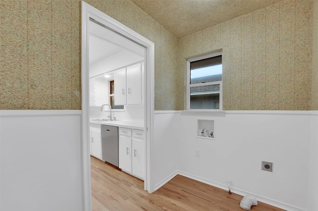 laundry room with electric dryer hookup, sink, hookup for a washing machine, and light hardwood / wood-style flooring