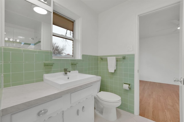 bathroom with vanity, wood-type flooring, tile walls, and toilet