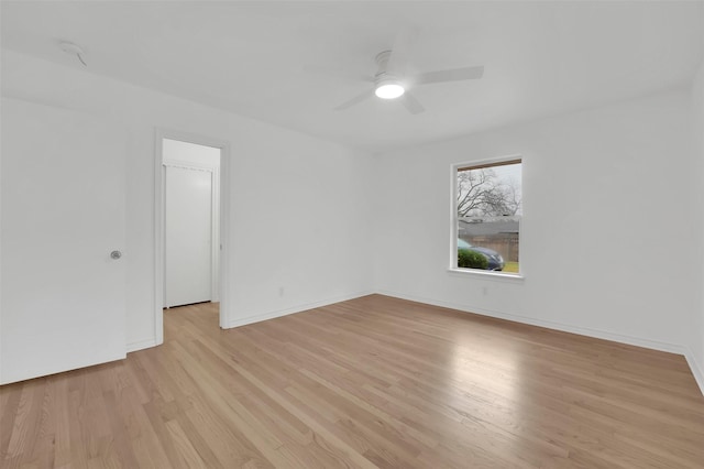 spare room with light wood finished floors, ceiling fan, and baseboards