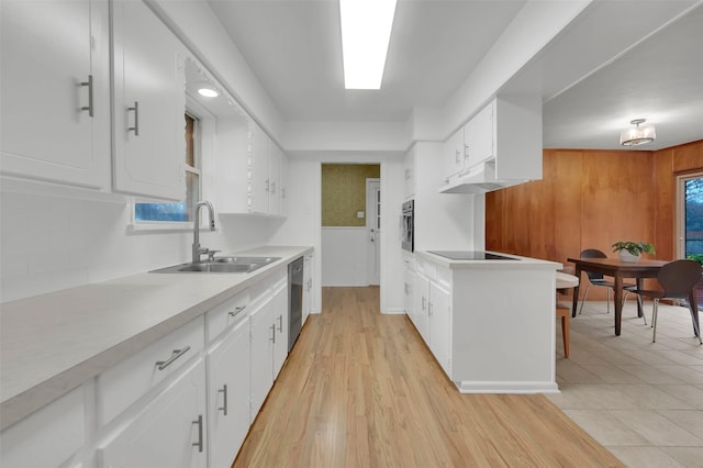 kitchen featuring appliances with stainless steel finishes, sink, white cabinets, decorative backsplash, and light hardwood / wood-style floors