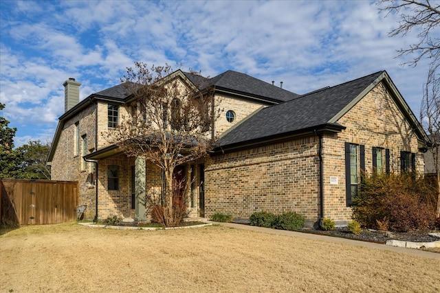 view of front of property featuring a shingled roof, a chimney, and brick siding